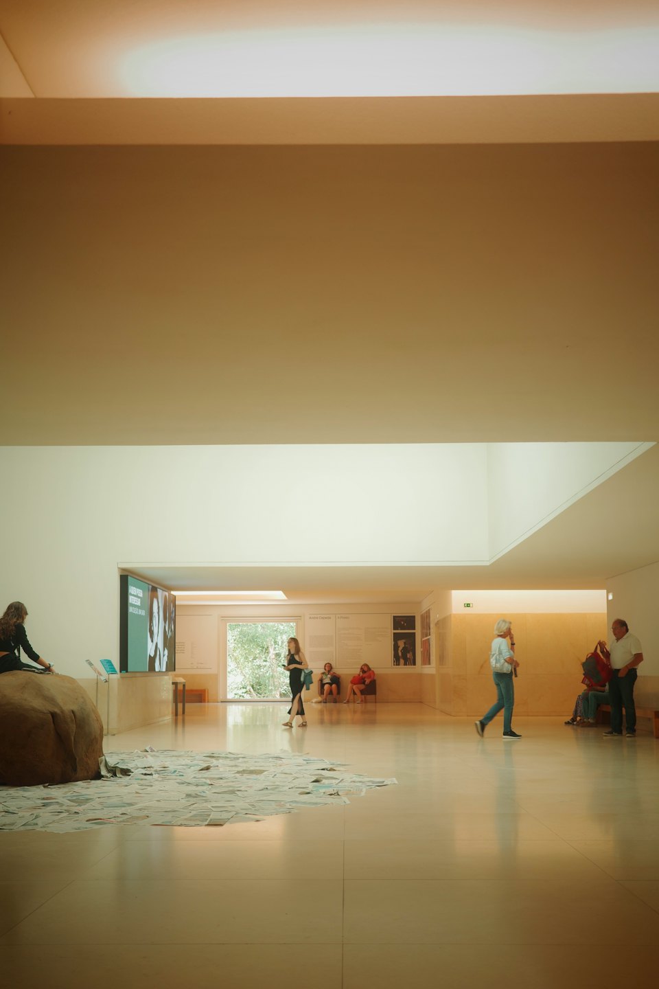 Visitors explore a modern art gallery with a large screen display.