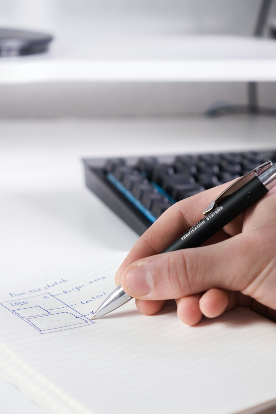 Hand sketching website wireframe with blue ink on notebook.
