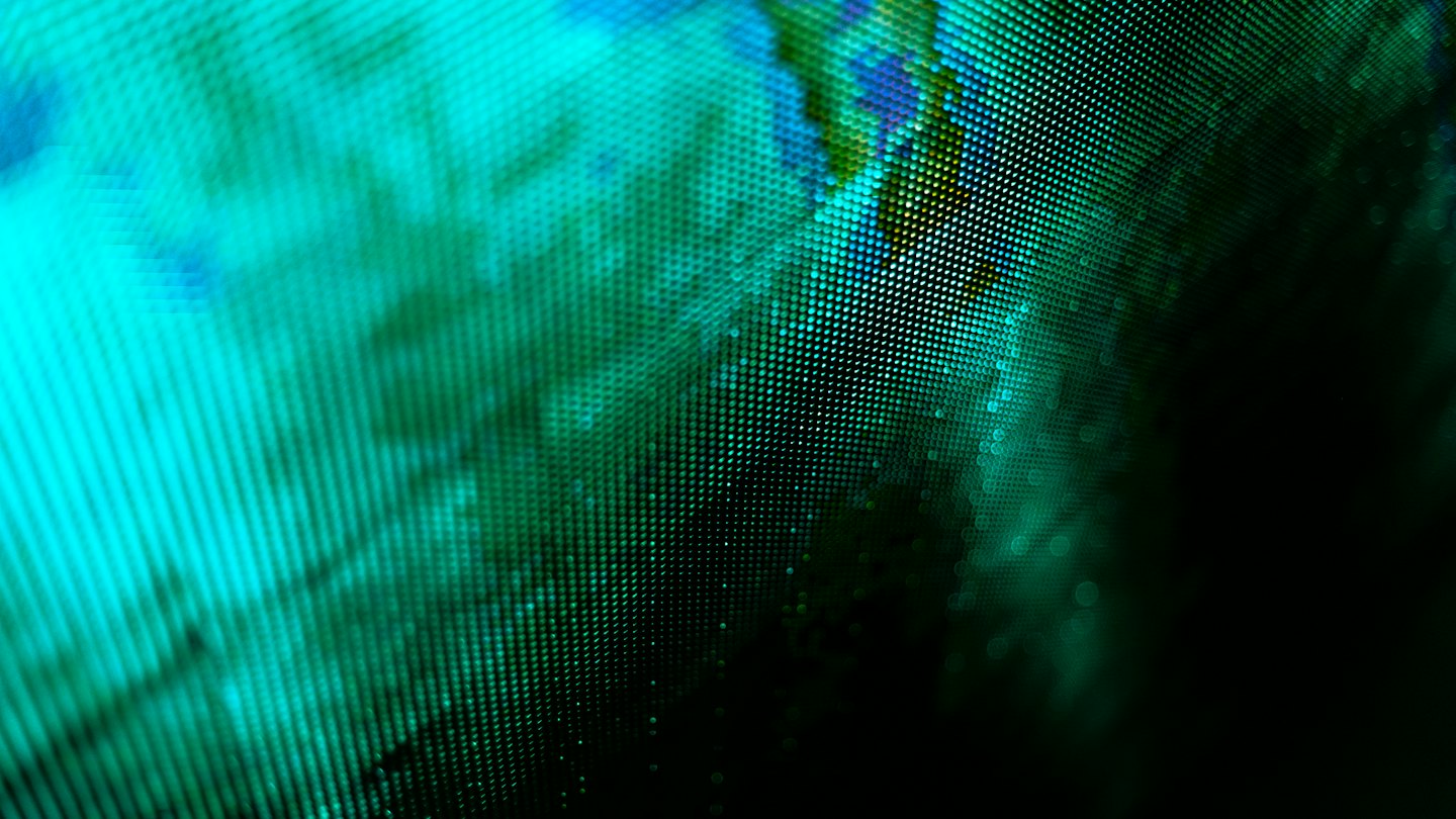 Close-up of a digital screen with teal, green, and blue pixels.